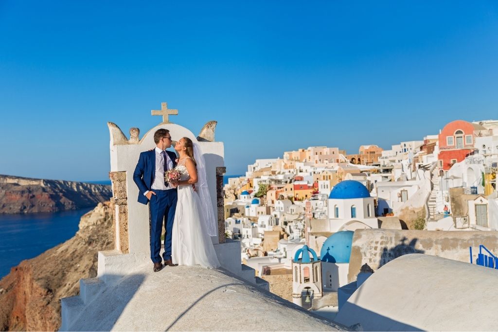 A couple getting married with Santorini in the background.