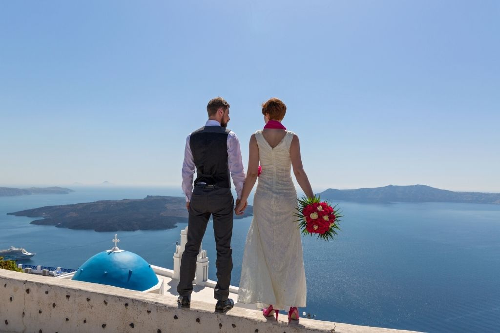 A man and woman standing on the edge of the walkway in Oia, Santorini.